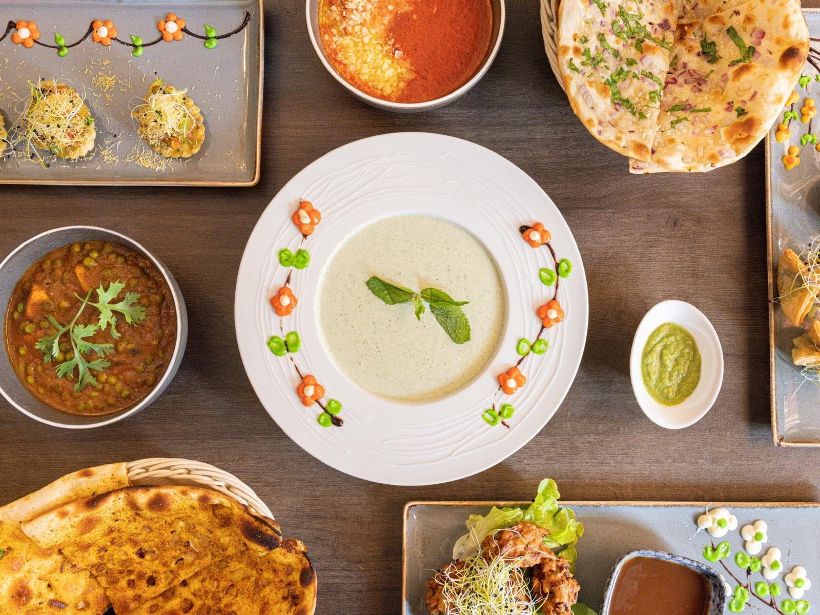 A table seen from above, set with soup, curries, naan and starters from the Tamarind Hill kitchen.