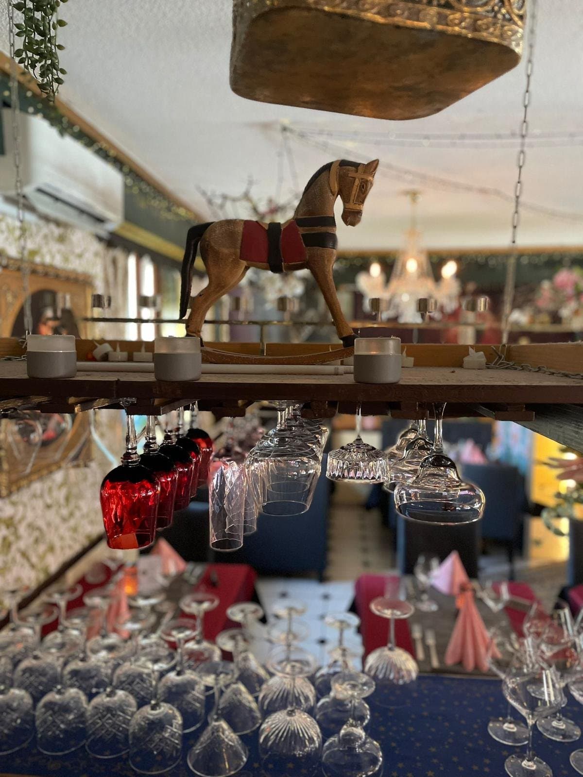 A wooden rocking horse above the bar, with glasses hanging underneath.