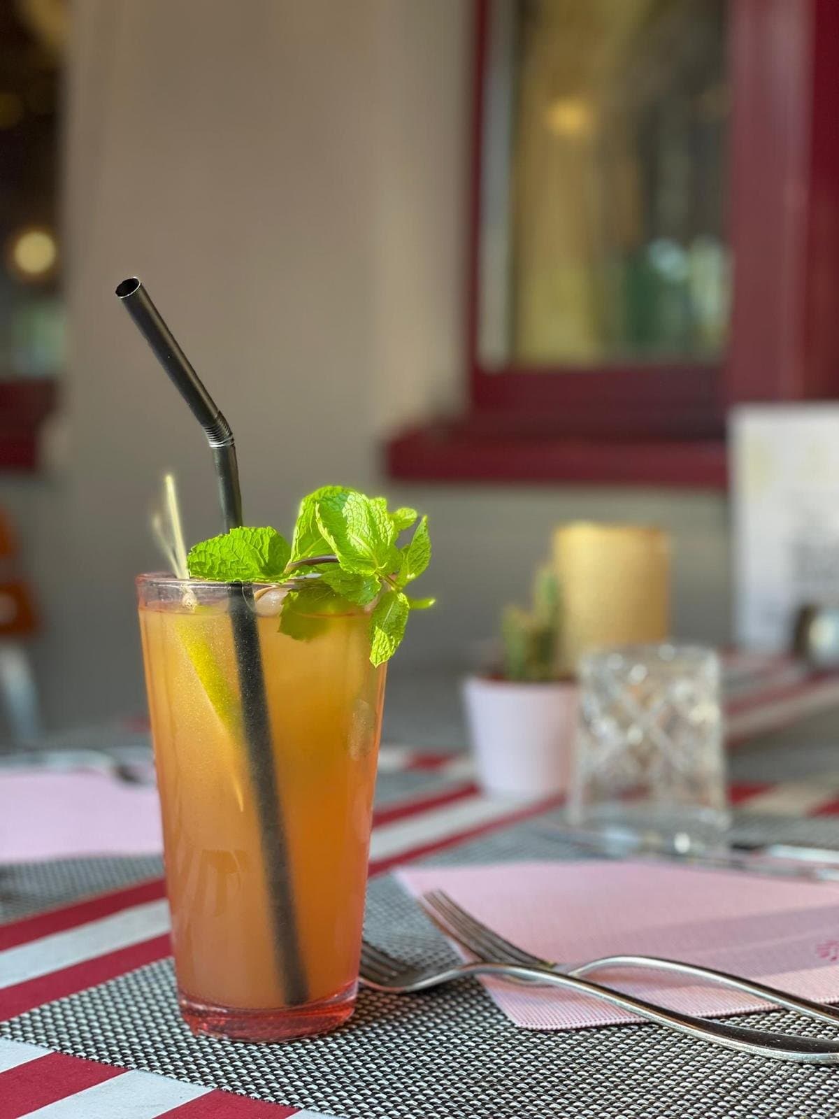 An iced drink with fresh mint and a lime wedge, on a terrace table.