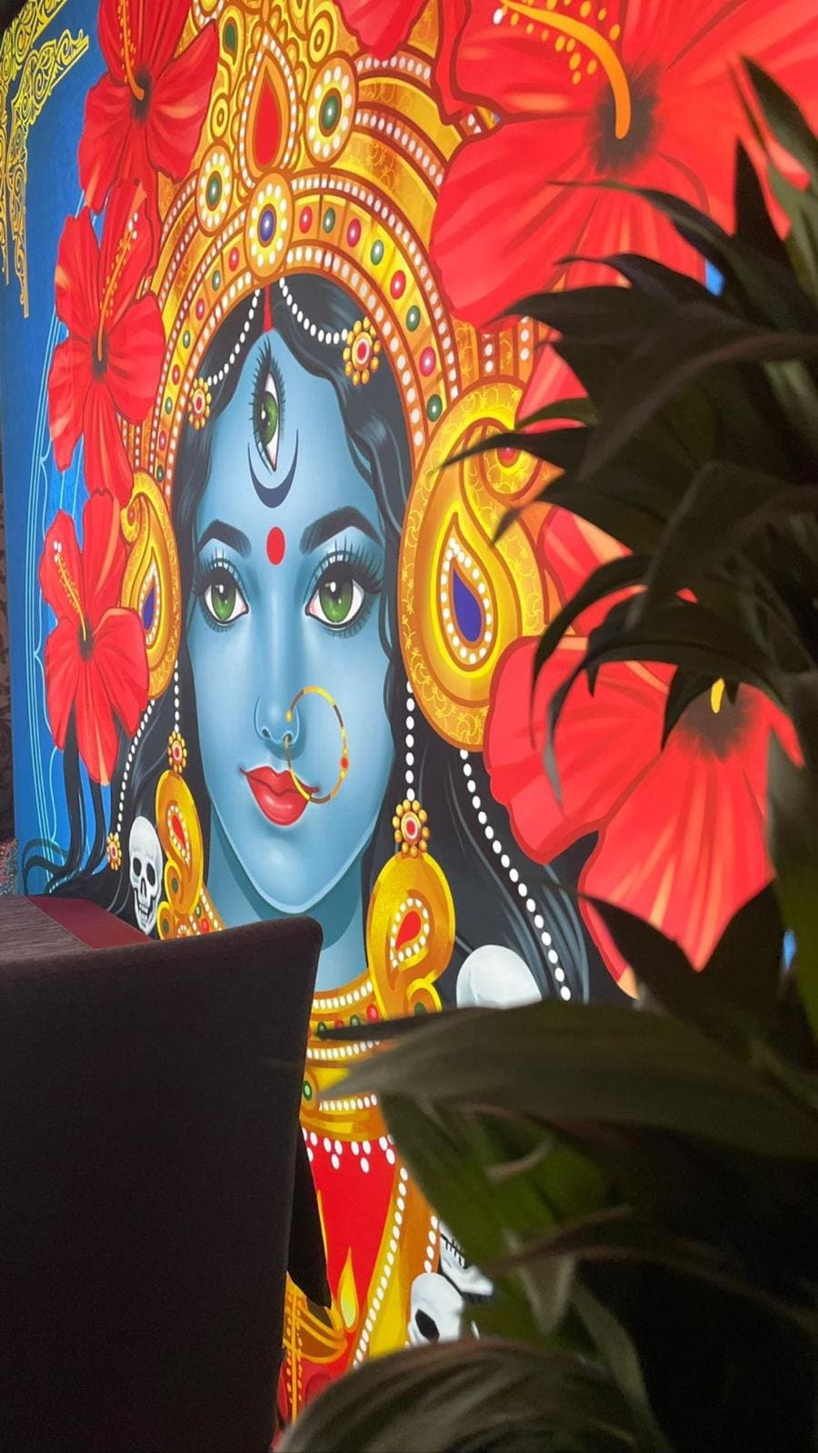 The painted mural of the goddess Kali with red hibiscus flowers.